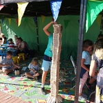 Namiot, pod którym dzieci na wykładzinie bawią się klockami, w pierwszym planie chłopiec zbudował wieżę wyższą od siebie