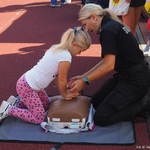 Funkcjonariuszka Straży Miejskiej instruuje dziewczynkę, jak wykonać masaż serca na manekinie przy udzielaniu pierwszej pomocy