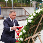 Prezydent Polski poprawia wstęgę na wieńcu złożonym pod pomnikiem