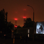 Pokaz iluminacji na budynku Muzeum Pamięci Sybiru, w tle rozświetlone na czerwono słupy elektrociepłowni