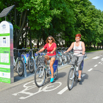 Dwie kobiety jadące na rowerach miejskich ścieżką rowerową