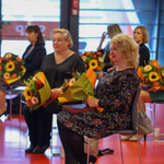 Laureaci nagrody siedzą trzymając kwiaty i grawertony
