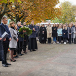 Po lewej stronie stoi Zastępca Prezydenta Rafał Rudnicki oraz nauczyciele składający wspólnie wieniec pod tablicą upamiętniającą ofiary wypadku
