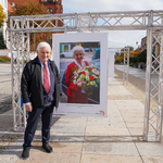 Starszy mężczyzna pozujący do zdjęcia przy wystawie zdjęć Karoliny Kaczorowskiej