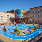 Uczniowie jeżdżą na rowerach po miasteczku ruchu drogowego