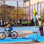 Uczniowie jeżdżą na rowerach po miasteczku ruchu drogowego