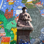 Pomnik Marii Konopnickiej stojący przy budynku szkoły, w tle widać mural