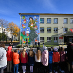 Szeroki kadr na uroczystość odsłonięcia muralu mająca miejsce przed budynkiem szkoły