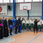 Po lewej stronie goście honorowi uroczystości wraz z duchownymi, po prawej śpiewa chór dziecięcy dyrygowany przez kobietę