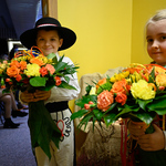 Dzieci ubrane w stroje ludowe stoją z bukietami kwiatów