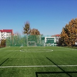 Centralny widok na boisko z nową, zieloną nawierzchnią