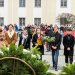Delegacja młodych osób idzie złożyć kwiaty przy pomniku