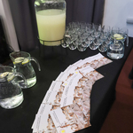 Broszurki szlaku kulinarnego leżące na stole, buza w szklanym nalewaku oraz szklanki