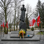 Pomnik księdza Popiełuszki przyozdobiony kwiatami i flagami