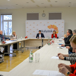 Spotkanie Rady Seniorów w sali, przy stołach ustawionych w literę O siedzą goście, z tyłu widoczna ścianka promocyjna Miasta Białystok