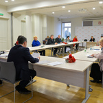 Spotkanie Rady Seniorów w sali, przy stołach ustawionych w literę O siedzą goście, z tyłu widoczna ścianka promocyjna Miasta Białystok