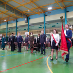 Poczet sztandarowy wprowadza sztandar szkoły na salę gimnastyczną, po lewej grono pedagogiczne oraz goście stoją przy krzesełkach