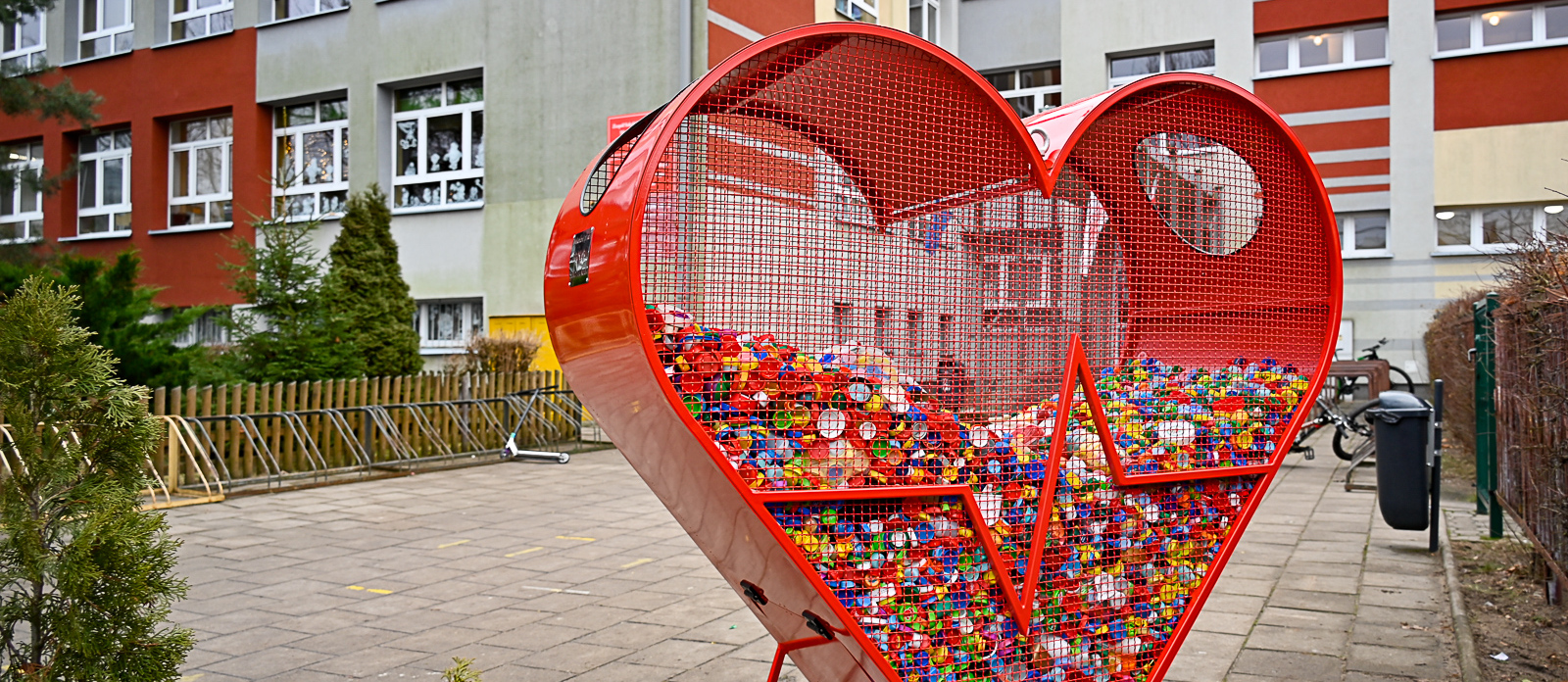 Pojemnik w kształcie serca stojący na placu przed szkołą