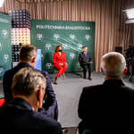 Rektor Marta Kosior-Kazberuk wraz z prowadzącym siedzą na krzesełkach na tle ścianki promocyjnej Politechniki Białostockiej