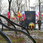 Pomnik przyozdobiony kwiatami od prezydenta Białegostoku, obok stoją żołnierze
