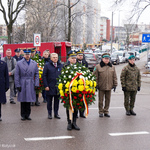 Prezydent Tadeusz Truskolaski składa okolicznościowy wieniec przy pomniku upamiętniającym katastrofę pociągu z chlorem. Asystują przedstawiciele służb mundurowych.