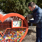 Zastępca prezydenta Rafał Rudnicki wrzuca do  czerwonego kosza w kształcie serca plastikowe nakrętki