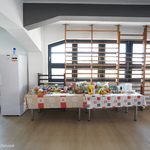 Lodówka i długi stół, na którym leży jedzenie w Miejskim Centrum Pomocy Uchodźcom