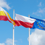 Na wietrze powiewają flagi: Polska, Unii Europejskiej i Miasta Białystok