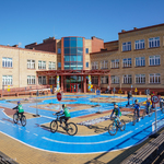 Dzieci jeżdżą na rowerach pod szkołą, w miasteczku ruchu drogowego