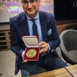 Zastępca prezydenta Rafał Rudnicki prezentuje medal URBI MERITUS Zasłużony Miastu