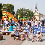 Uczestnicy festynu spacerują, siedzą na leżakach, korzystają z atrakcji