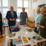 Prezydent Tadeusz Truskolaski ogląda stworzone przez seniorów przedmioty, np. czapkę i szalik