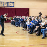 Mężczyzna gra na skrzypach przed publicznością zgromadzoną w auli