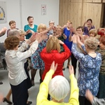 Seniorzy tańczą w kółku podczas zabawy