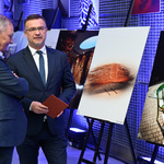 Zastępca prezydenta Adam Musiuk podczas rozmowy z mężczyzną, w tle: wystawa