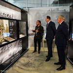Prezydent Tadeusz Truskolaski, Mark Brzezinski oraz pracownik Muzeum Pamięci Sybiru stoją przed gablotą z fotografiami