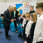 Prezydent Tadeusz Truskolaski wręcza dzieciom plecaki z wyposażeniem