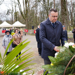 Zastępca prezydenta Rafał Rudnicki poprawia szarfę przy wieńcu