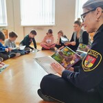 Na zdjęciu widać funkcjonariusza Straży Miejskiej, który wraz z dziećmi czyta bajkę