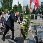 Zastępca prezydenta Przemysław Tuchliński poprawia kwiaty przy pomniku