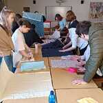 Młodzież z Polski, Węgier i Czech wybierają i wycinają materiały podczas warsztatu szycia toreb wielorazowego użytku