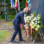 Przewodniczący Łukasz Prokorym poprawia wieniec kwiatowy