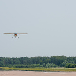 Mały samolot (Cessna 152) leci na niebie, nad pasem lotniczym Krywlany