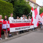 Uczestnicy spotkania stoją na chodniku z banerem z napisem ,,Solidarni z Białorusią