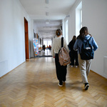 Uczennice spacerują po korytarzu szkolnym, na plecach mają plecaki