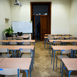 Sala lekcyjna, w której znajdują się drewniane ławki z krzesłami oraz tablica