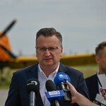 Zastępca prezydenta Rafał Rudnicki zabiera głos podczas konferencji prasowej, w tle: samolot