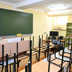 Sala lekcyjna, w której znajdują się ławki szkolne, krzesła oraz tablica