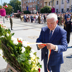 Prezydent Tadeusz Truskolaski poprawia szarfę znajdującą się na kwiatowym wieńcu 