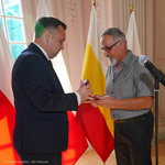 Zastępca prezydenta Przemysław Tuchliński przekazuje medal ,,Urbi Meritus- Zasłużony Miastu